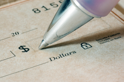 Close-up of a person filling out a dollar amount on a check, focus is sharp and on the pen tip and the dollar word and symbol.